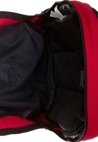 Mochila roja con apertura con cremallera, que presenta un interior negro acolchado y una textura de tela suave. Incluye bolsillos de almacenamiento interiores.