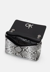 Borsa a tracolla in stampa serpente bianco e nero, realizzata in materiale testurizzato. Presenta un elegante interno nero con accessori in metallo argentato e un dettaglio con il logo.