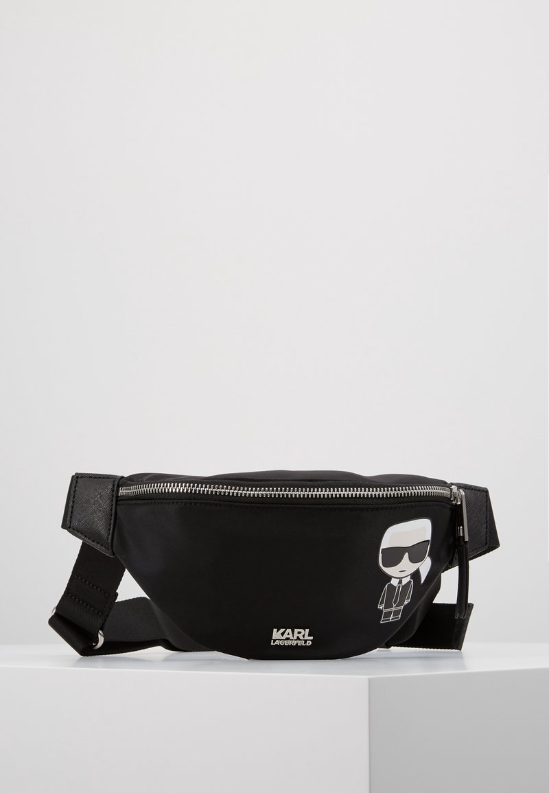 Sac banane noir Karl Lagerfeld avec fermeture éclair frontale, sangle ajustable et personnage de dessin animé portant des lunettes de soleil sur le côté droit.