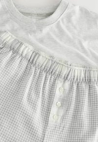 Hanorac gri și pantaloni de pijama în carouri cu talie elastică, având patru nasturi pe lateral și o textură moale.