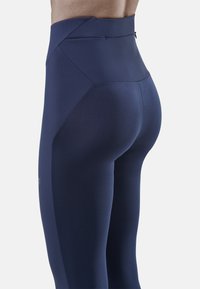 Marineblaue Hochbund-Leggings mit nahtlosem Design, konturierenden Akzenten und einer glatten, elastischen Textur für Komfort und Beweglichkeit.