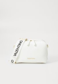 Vit texturerad skinnhandväska med dragkedjestängning, utrustad med en märkesbeklädd svart rem och guldfärgade detaljer. Kompakt rektangulär form.