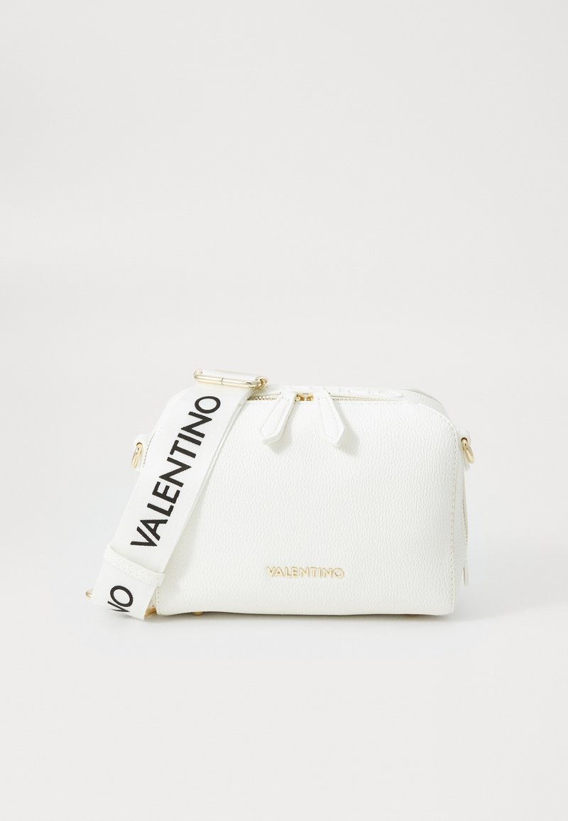 Vit texturerad skinnhandväska med dragkedjestängning, utrustad med en märkesbeklädd svart rem och guldfärgade detaljer. Kompakt rektangulär form.