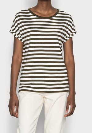 Person trägt ein kurzärmeliges, olivgrün-weiß gestreiftes T-Shirt mit horizontalen Streifen und off-weiße Hose, steht vor einem schlichten Hintergrund.