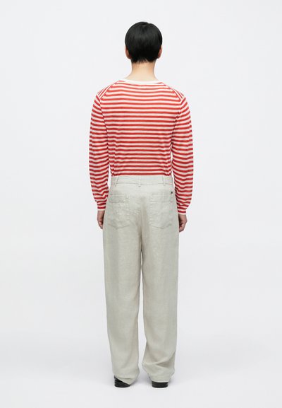 Chemise à manches longues rayée rouge et blanche, associée à un pantalon en lin gris clair avec deux poches arrière, vue de dos.