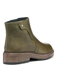 Bottines en cuir vert olive avec une texture lisse, bout rond et semelle à motif marron moyen. Présentent un détail de bouton pression sur le côté.