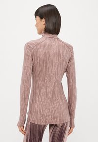 Kitsas, pika varrukaga topp heledas lilas, millel on peene, vertikaalseid jooni kujundus. Omab mock kaela ja kujundatud õmblusi.