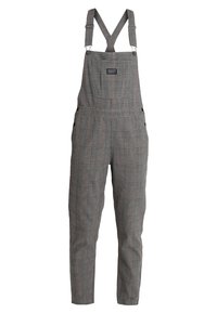 Grau karierte Latzhose mit verstellbaren Trägern, einer Fronttasche und Seitenschaltern. Hergestellt aus einem strukturierten Stoff, der für Komfort und Funktionalität sorgt.