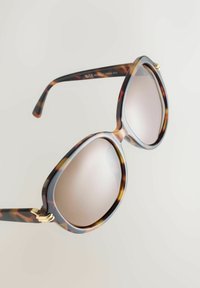 Brūngani saulesbrilles ar bruņurupuča raksta rāmjiem, apaļu formu, brūnām lēcām un zelta detaļām uz kājiņām. Gluda plastmasas materiāla.