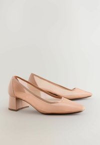 Pantofi nude din piele patent cu toc bloc, cu vârf ascuțit și panouri laterale din plasă transparentă, având o textură netedă și un design minimalist.