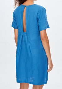 Vestido de lino azul con mangas cortas, que presenta un corte en la espalda y un detalle de plisado. La tela tiene un acabado texturizado.
