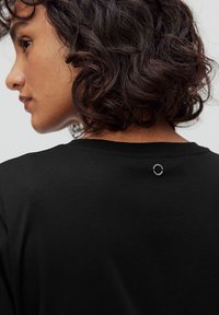 Mustapaita, jossa on pyöreä pääntie ja pieni pyöreä varuste takana. Paita on valmistettu pehmeästä kankaasta, jonka pinta on sileä.