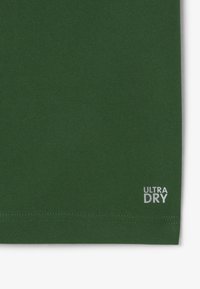 Tessuto verde scuro con una finitura testurizzata. Presenta un logo bianco "ULTRA DRY" vicino al bordo inferiore. Design semplice, senza ulteriori motivi o decorazioni.