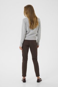 Maglione grigio chiaro, pantaloni aderenti marroni, scarpe nere, modellato di spalle, con una texture liscia e un design minimalista.