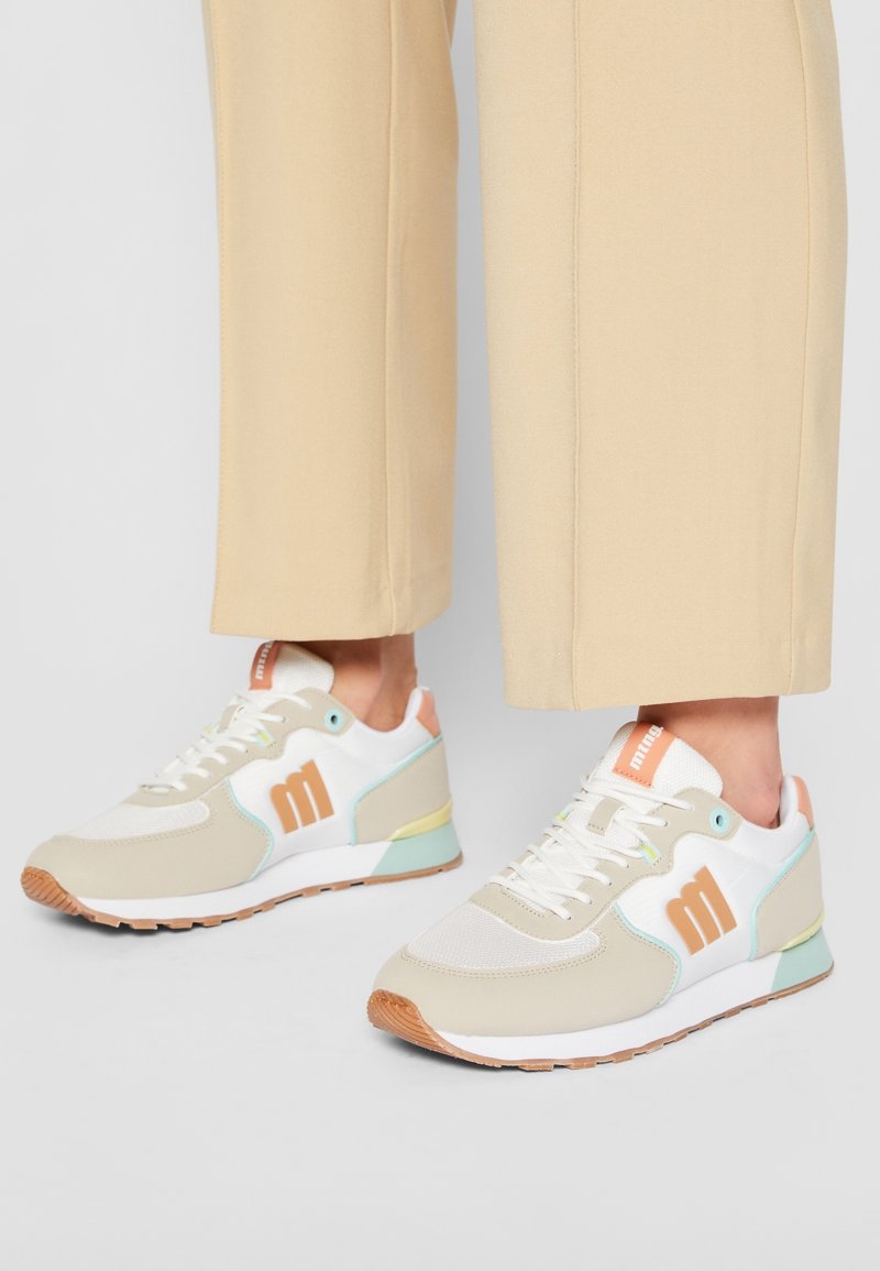 Baskets légères en crème, beige et vert menthe avec une semelle en caoutchouc texturée. Présentent des accents colorés et un dessus en maille pour la respirabilité.