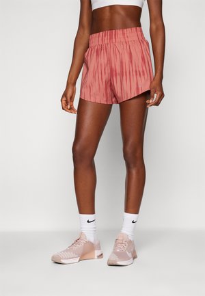 Roze tie-dye sportshorts met een elastische tailleband, gecombineerd met witte Nike-sokken en lichtroze Nike-sneakers. Soepele stoftextuur.
