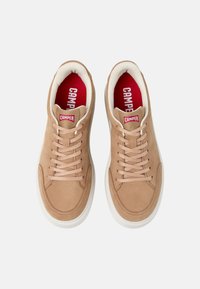 Tan suede sneakers with a smooth texture, white rubber soles, and beige laces. Red "CAMPER" logo on tongue and a contrasting inner lining.