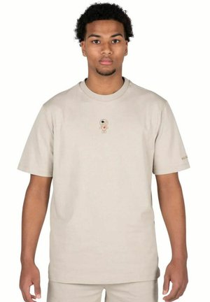 Lichtbeige t-shirt met korte mouwen van katoen, met een klein geborduurd figuurtje met een oog en hartontwerp op de borst.