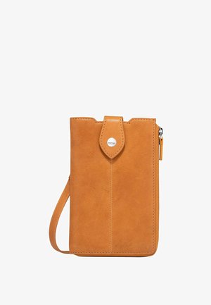 Tan leather wallet with a flap closure, featuring a circular silver logo and a side zipper. Slim rectangular shape with a wrist strap.