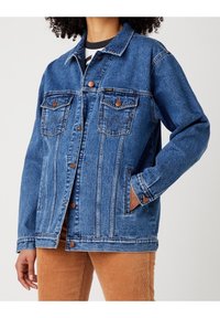 Světle modrá džínová bunda s límečkem, zapínáním na knoflíky, dvěma náprsními kapsami a kontrastním prošíváním. Má dlouhé rukávy a volný střih.