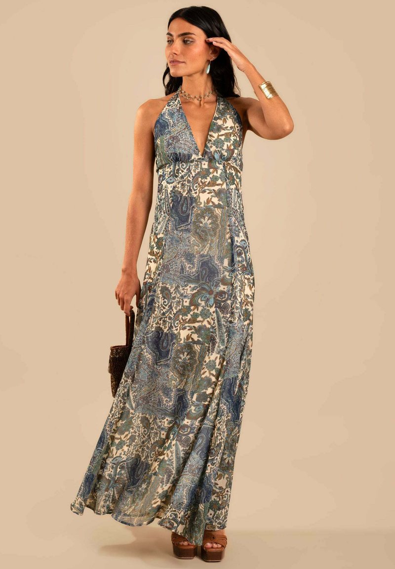 Vestido maxi con un escote en V profundo, con un patrón de paisley azul y verde en una tela ligera, combinado con sandalias de plataforma marrones.