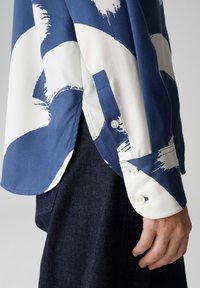 Marineblaues und weißes langärmeliges Hemd mit abstraktem Pinselstrichmuster, mit geknöpftem Manschetten und seitlichen Schlitzen, gefertigt aus glattem Stoff.