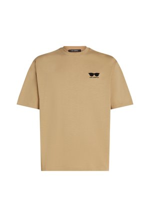 Beige bomulls t-shirt med kort ärm. Har en svart logotyp av solglasögon och varumärkesnamn på vänster bröstområde. Rund halsringning.