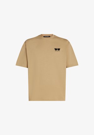 Bež bombažna majica s kratkimi rokavi. Ima črni logotip sončnih očal in ime blagovne znamke na levi strani prsnega dela. Okrugli izrez.