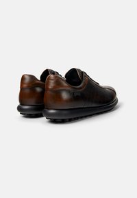 Brown leather shoes with a smooth texture, rounded shape, black laces, and a textured black sole, featuring subtle stitching accents.