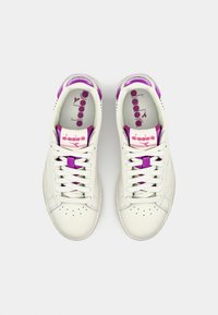 Un paio di sneaker bianche in pelle con accentuazioni e lacci viola, viste dall'alto su uno sfondo bianco uniforme.
