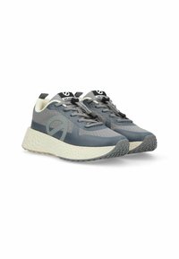 Scarpe da allenamento grigie con una tomaia texturizzata, dettagli riflettenti e una suola bianca spessa, dotate di lacci grigio scuro e un manico per il rilascio.