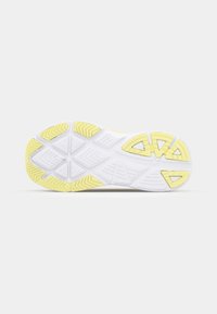 Semelle de chaussure avec une base blanche et des accents jaunes texturés. Comprend un motif de rainures en zigzag pour une traction et une stabilité.