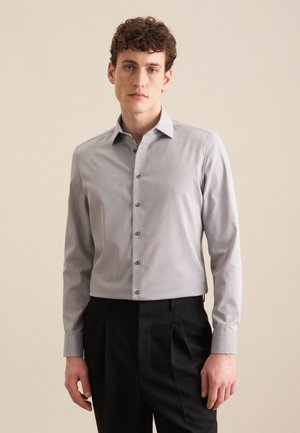 Lichtgrijze blouse met lange mouwen en een button-down kraag, voorzien van subtiele streepjes en donkere knopen, gecombineerd met zwarte trousers.