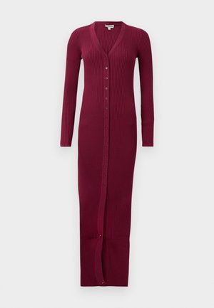 Bordeaux geribbelde lange cardigan met een V-hals, lange mouwen en een knoopsluiting aan de voorkant. Heeft een split aan de onderkant voor bewegingsvrijheid.