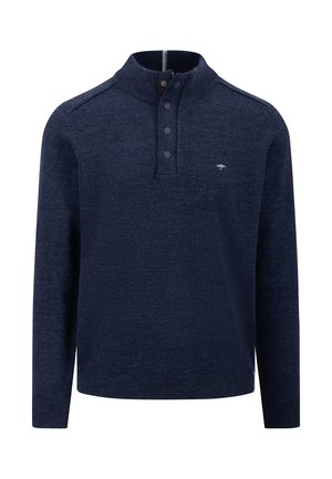 Mørkeblå strikket pullover med høj krave, fire knapper og et diskret logo på brystet. Har lange ærmer og ribbet kant.