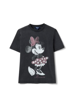 T-shirt noir à manches courtes présentant Minnie Mouse de style vintage, portant une jupe et un nœud rose à pois, debout les mains sur les hanches.