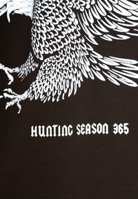 Black t-shirt featuring a white graphic of an eagle with detailed feathers and the text "HUNTING SEASON 365" in a bold, gothic font.