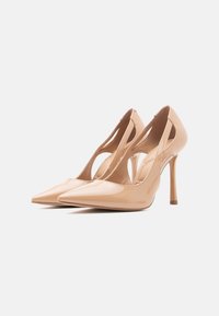 Chaussures à talons aiguilles en cuir verni couleur nude, à bouts pointus et design latéral ajouré. Caractérisées par des talons aiguilles fins et une texture lisse.