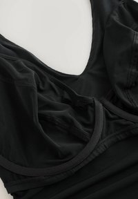 Juoda sportinė palaidinė iš lygaus sintetinio audinio. Turi apvalų iškirptę, struktūruotą dizainą ir siūtas detales visame paviršiuje.