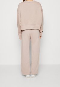 Ljusrosa sweatshirt och vida sweatpants i mjukt tyg. Har en kortad design med sänkta axlar och ribbade muddar.