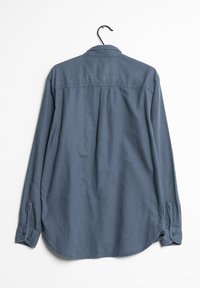 Košile s dlouhým rukávem, světle modrá, vyrobená z texturované tkaniny. Obsahuje límec na knoflíky a knoflíkové manžety. Zaoblený lem s plisovaným zadním detaily.