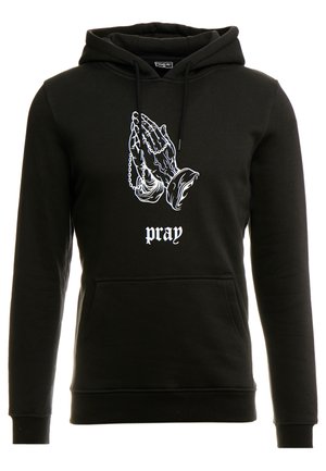 Schwarzer Hoodie mit einer Frontgrafik von betenden Händen in Weiß, versehen mit dekorativen Kettendetails. Der Text darunter lautet "pray" (beten). Weiches, texturiertes Material.