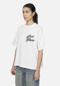 T-shirt bianca in cotone con vestibilità ampia, con maniche corte e una stampa grafica nera "Good for Nothing" sul davanti.