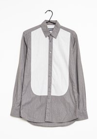 Harmaa raidallinen pitkähihainen paita, jossa on edessä suuri valkoinen kangas, nappikiinnitys ja taitettu kaulus. Kankaan pinta on sileä.