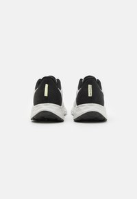 Zapatillas de deporte en blanco y negro con parte superior de malla transpirable, diseño texturizado, acentos reflectantes y suela acolchada.