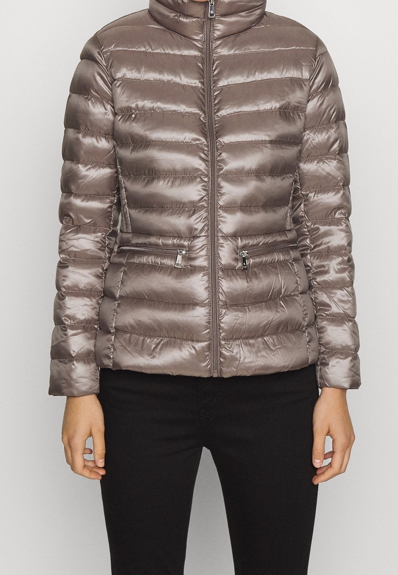 Vadderad jacka med dragkedja i metallic taupe med hög krage och horisontellt quiltad design; har två dragkedjeförsedda framlappar.