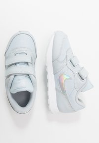 Sneakers azzurri chiari realizzati con materiali in tessuto e sintetici, dotati di due fasce in velcro, fodera in rete e un accento di logo riflettente.