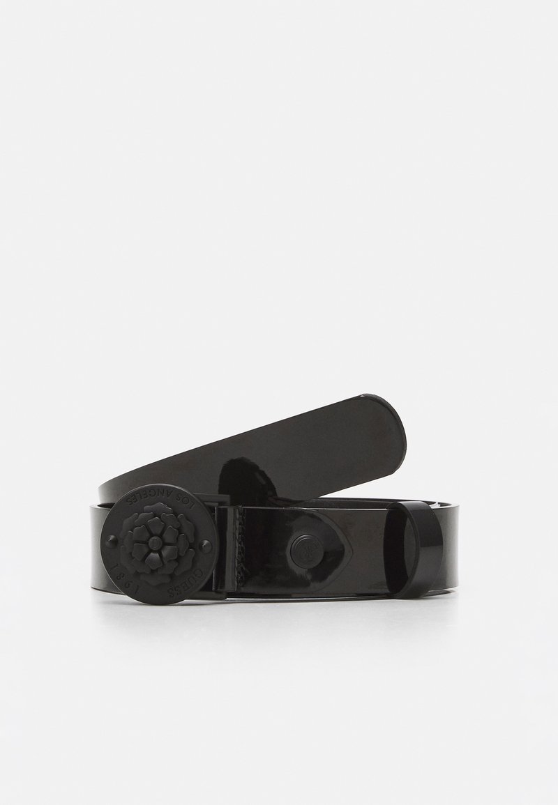 Czarny błyszczący pasek z okrągłą klamrą z tłoczonym kwiatowym wzorem i pętlą, zwinięty na białym tle.