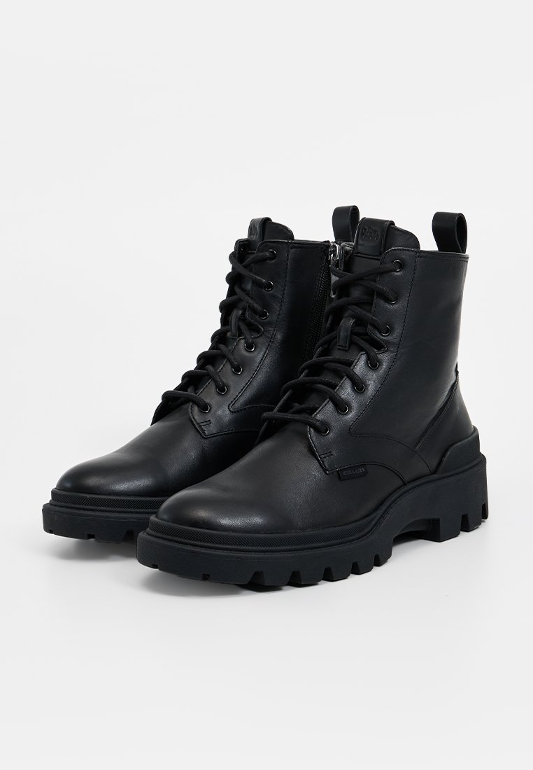 Bottines en cuir noir avec semelles en caoutchouc épaisses et chunky, bouts ronds et laçage à l'avant. Comprend une fermeture éclair sur le côté et une languette pour un enfilage facile.