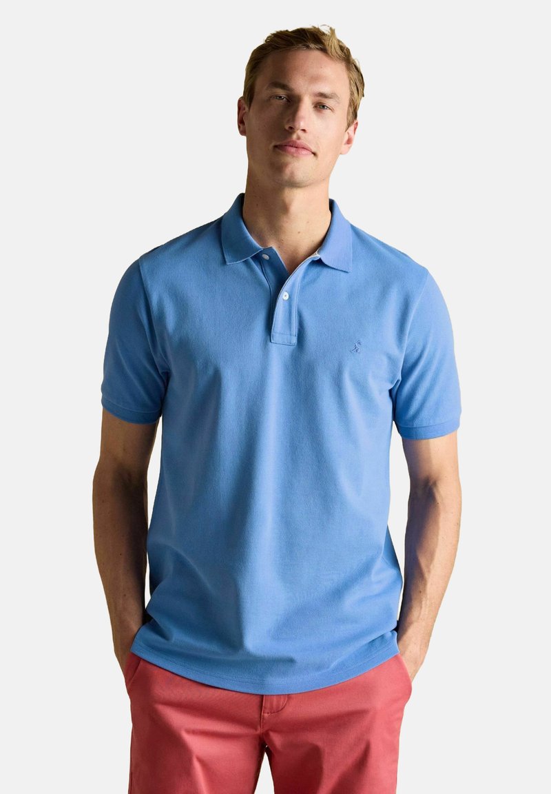 Heledsinine polo särk, mis on valmistatud puuvillast, klassikalise kraega, lühikeste varrukatega ja rinnal väikese tikitud logoga.